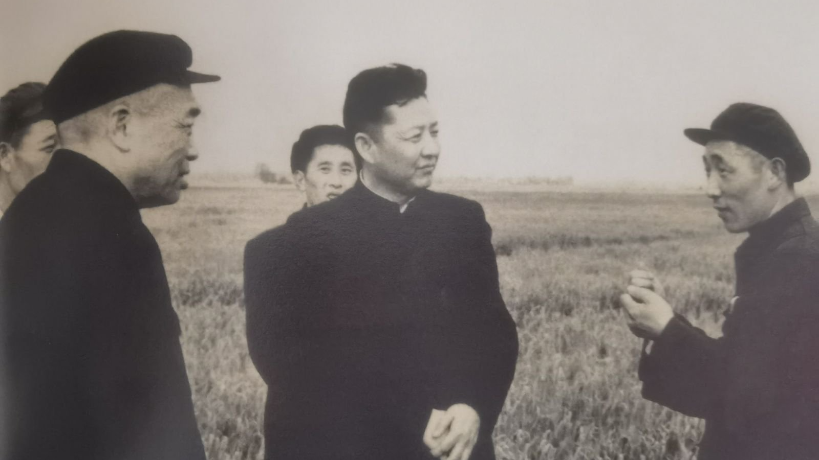 Xi Zhongxun (center) chats with a farmer in an undated photo. /CMG